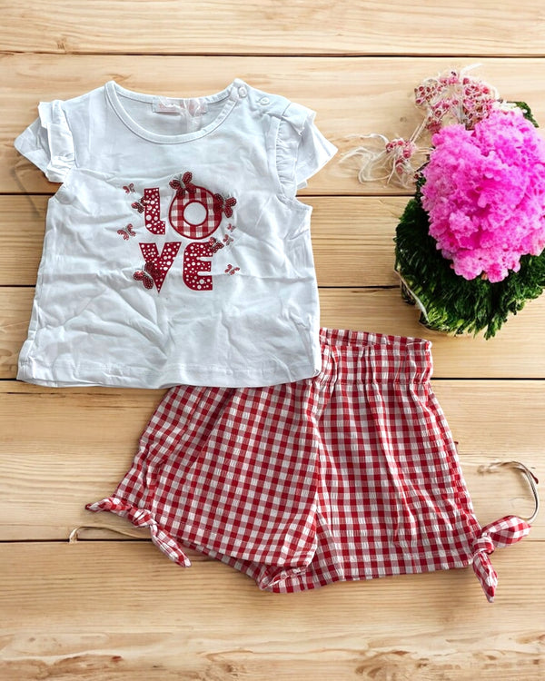 C-5830 - Completo con t-shirt decorata e shorts a quadretti con fiocchetti laterali. Un look fresco e vivace per ogni occasione.