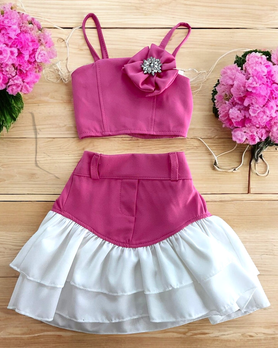 38190 - Completo elegante da bambina in due pezzi, con top a spalline e fiore decorativo con dettaglio gioiello. Gonna a balze morbide, ideale per occasioni speciali.